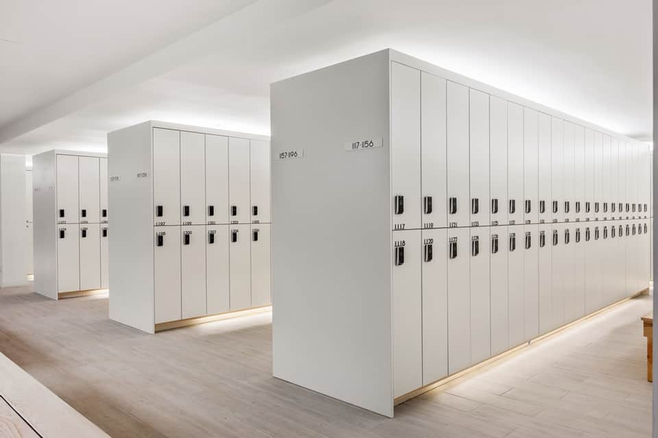 Modern white locker room with numbered storage units and natural lighting
