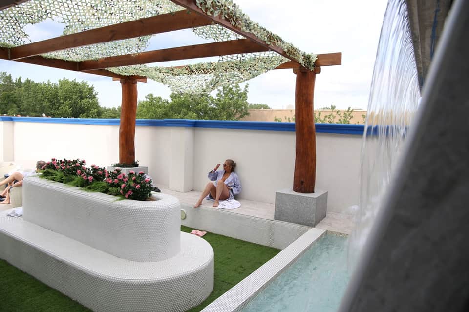 Poolside lounge area with modern seating, pergola shade, and water feature