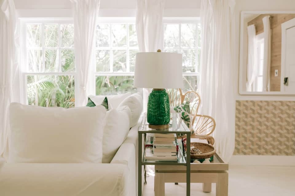 Bright coastal room with large windows, white furnishings, and tropical views