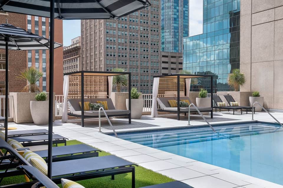 Modern rooftop pool overlooking downtown city skyline with lounge chairs and shade structures