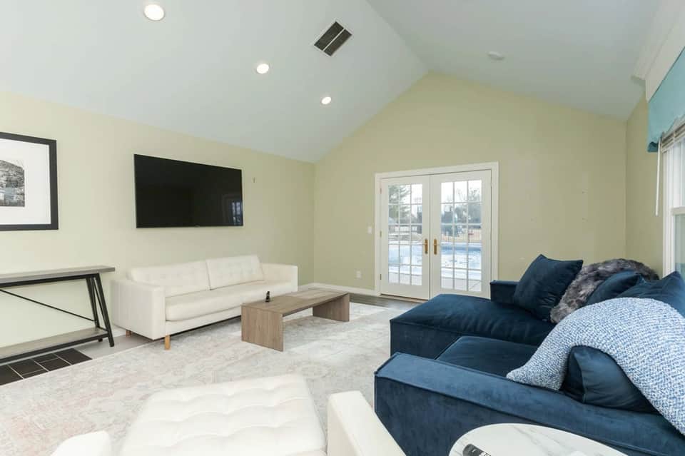 Bright living room with fireplace, blue and white seating, and glass doors to pool