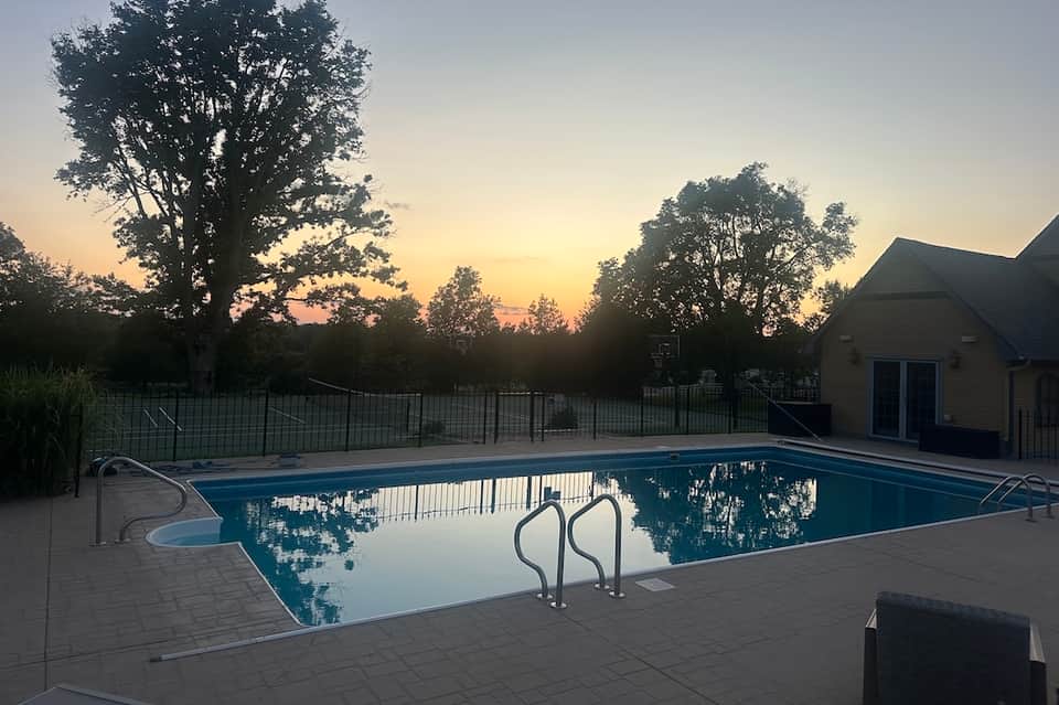 Outdoor swimming pool at dusk with metal railings and cottage-style pool house