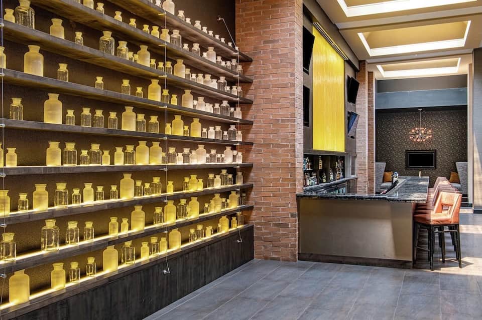 Spa reception area with illuminated yellow bottles on shelves and brick accents