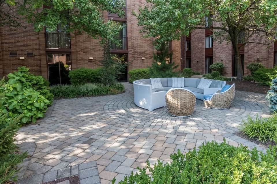 Urban courtyard with curved modular seating in neutral tones on a patterned brick patio