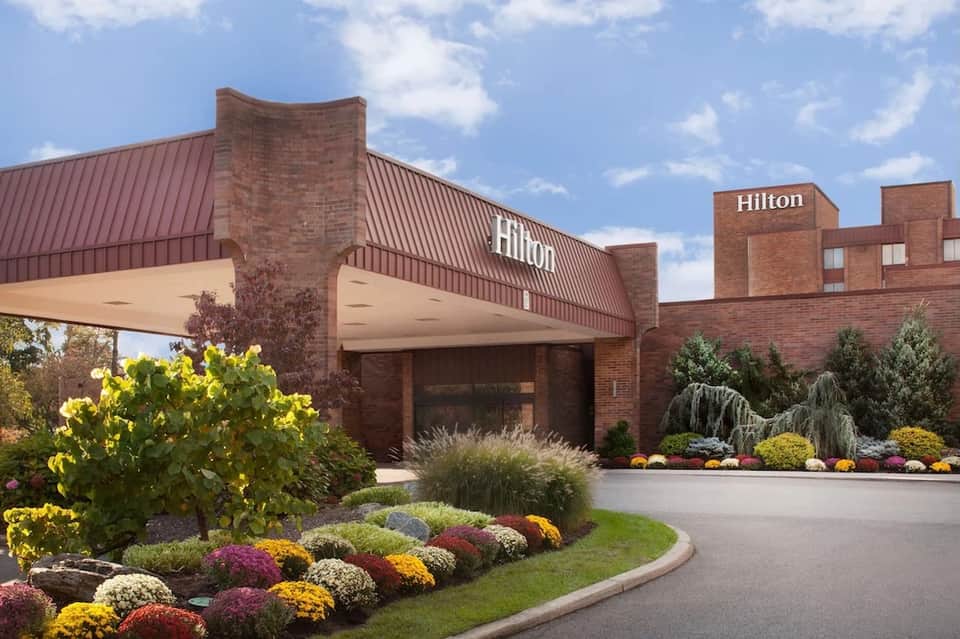 Hilton hotel entrance with brick façade, landscaped garden with colorful flowers