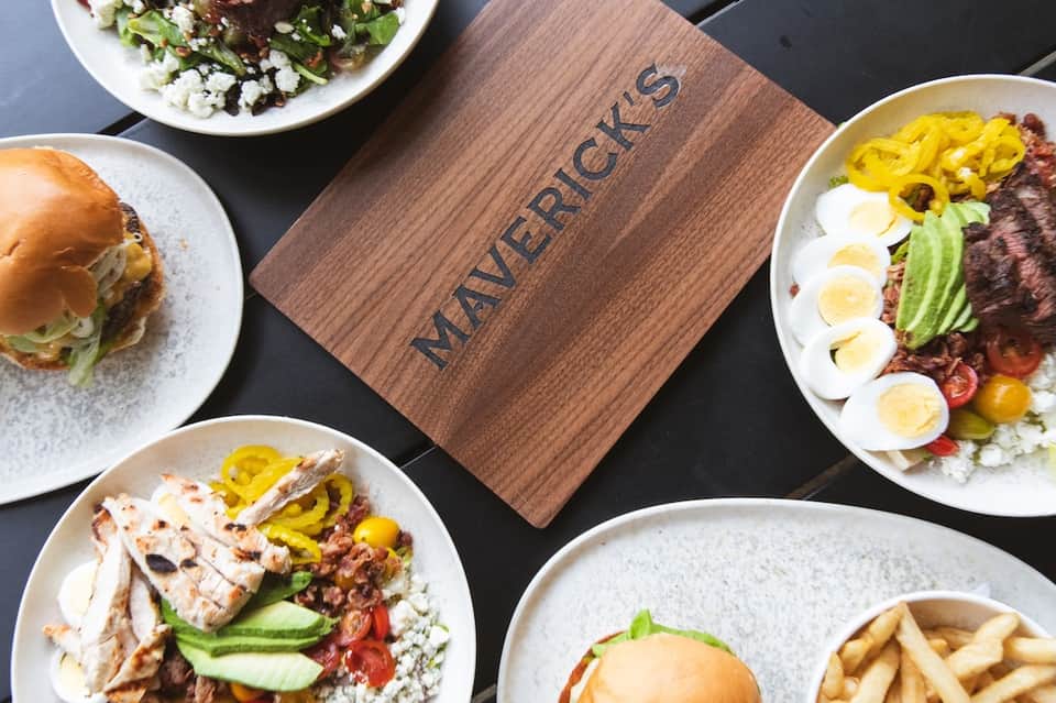 Restaurant plating display with burger, salads, and egg dishes on white and gray plates