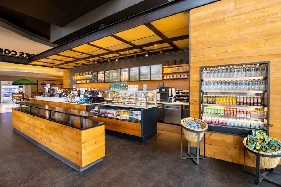 Casual beach café with wooden counter, menu boards, and refrigerated beverage displays