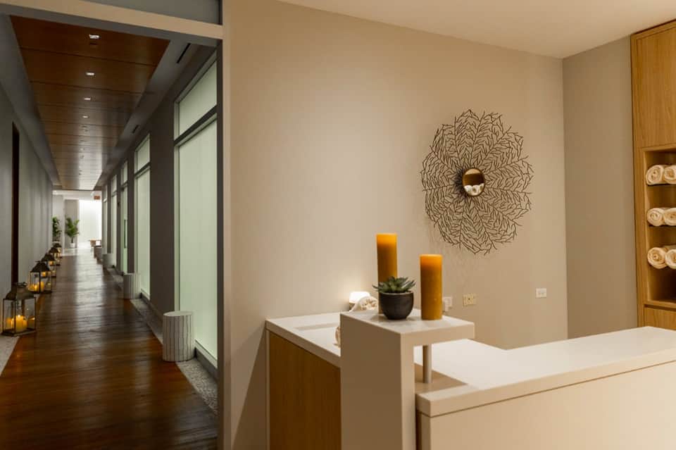 Spa reception area with minimalist design, wooden ceiling details, wall art, and hallway leading to treatment rooms