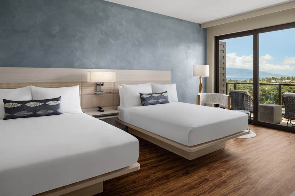 Modern hotel bedroom with two beds, ocean view balcony, and contemporary furnishings