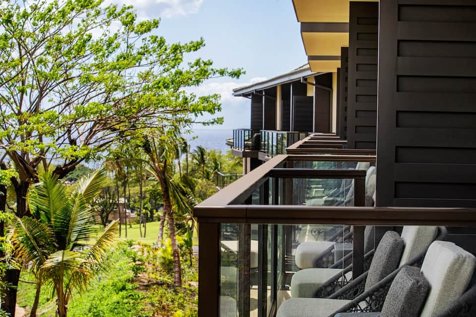 Modern home balcony with mountain views, tropical vegetation, and contemporary furnishings