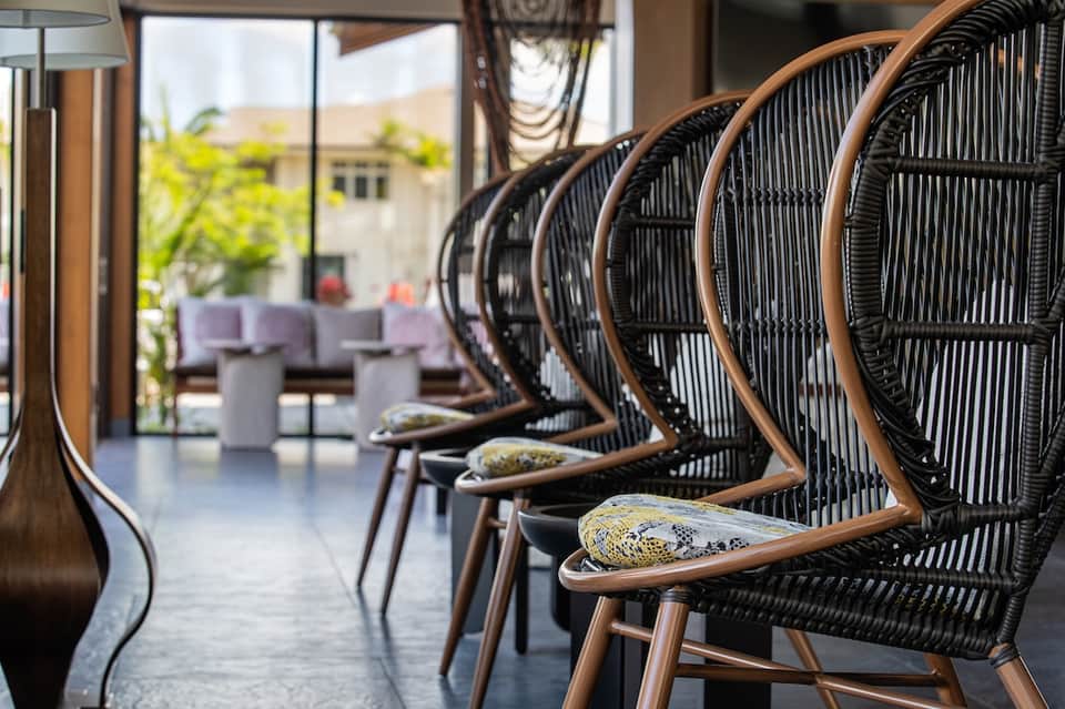 Woven rattan chairs in beige and black arranged in resort lounge with ocean views