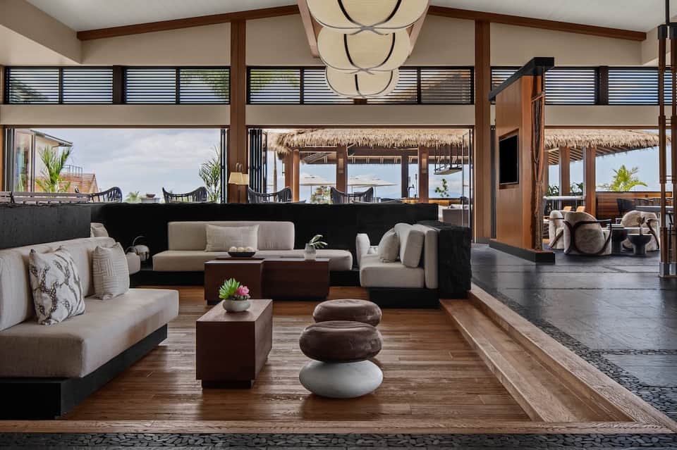 Spacious resort lounge with beige seating, wood accents, and ocean views through large windows