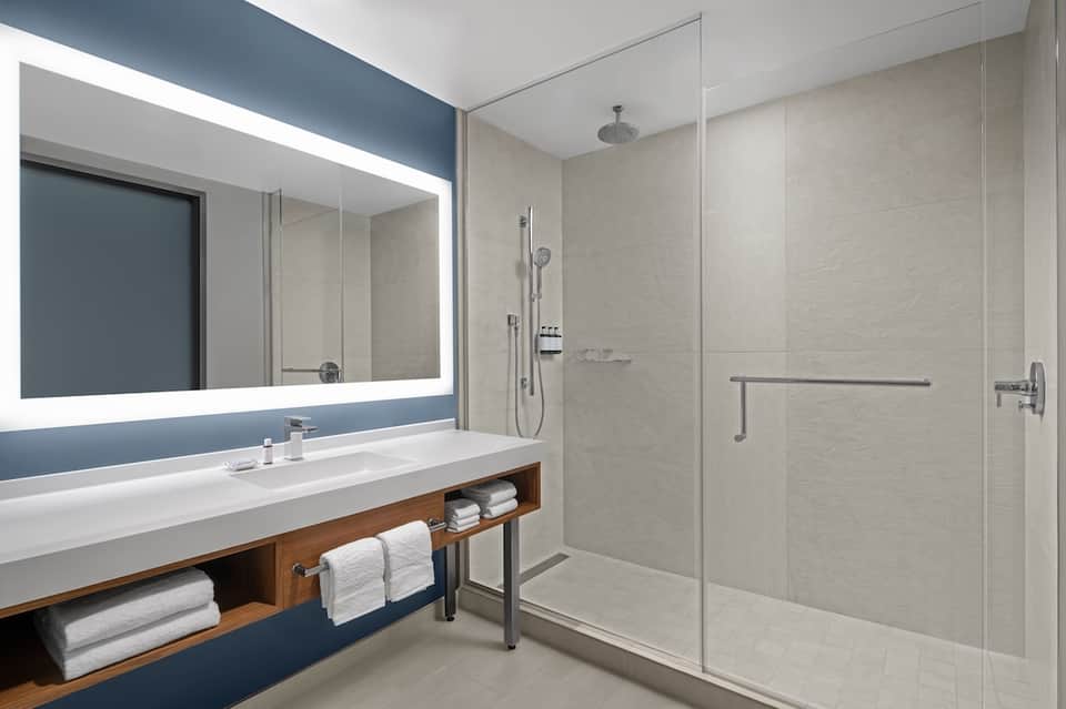 Modern bathroom with illuminated mirror, floating vanity, and rainfall shower