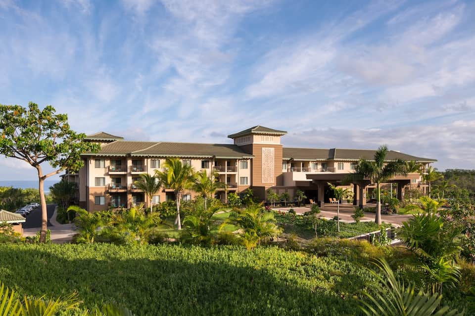 Luxury resort building exterior with tropical landscaping, palm trees, and manicured grounds