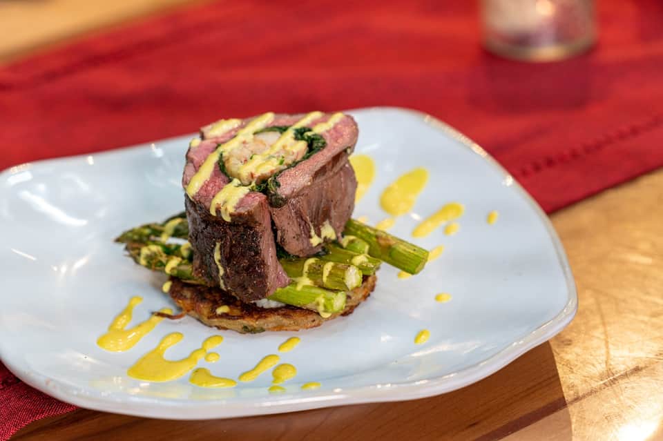 Gourmet plated beef dish with asparagus and yellow sauce on white plate