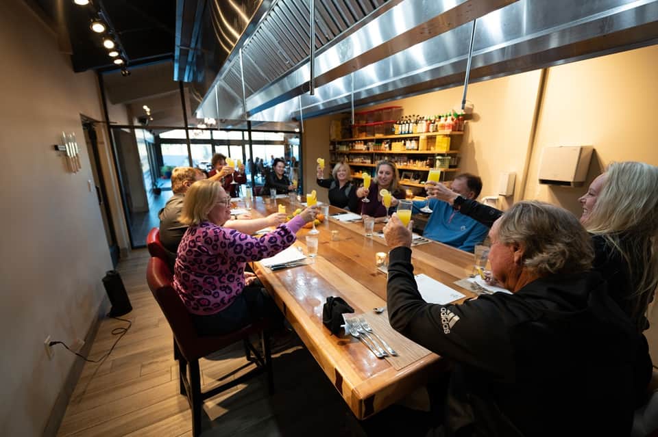 Hotel dining area with guests seated at long wooden table under high ceilings and professional lighting