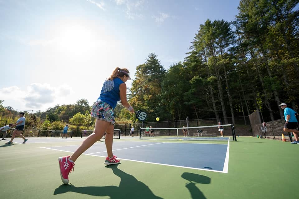 Female tennis player in action on outdoor courts at active community sports facility