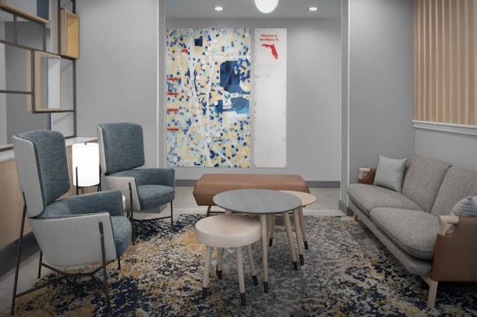 Modern lobby lounge with blue chairs, round table, and colorful wall art