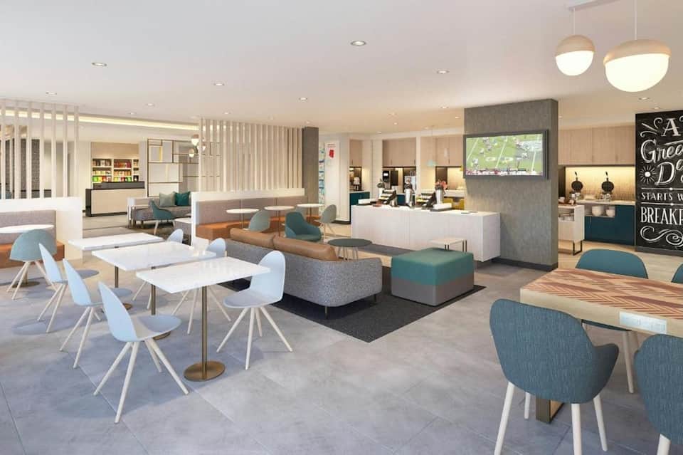 Modern hotel lobby lounge with seating areas, kitchen, and contemporary decor