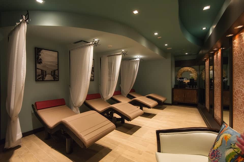 Luxury spa relaxation room with lounge chairs, curtains, and ambient lighting