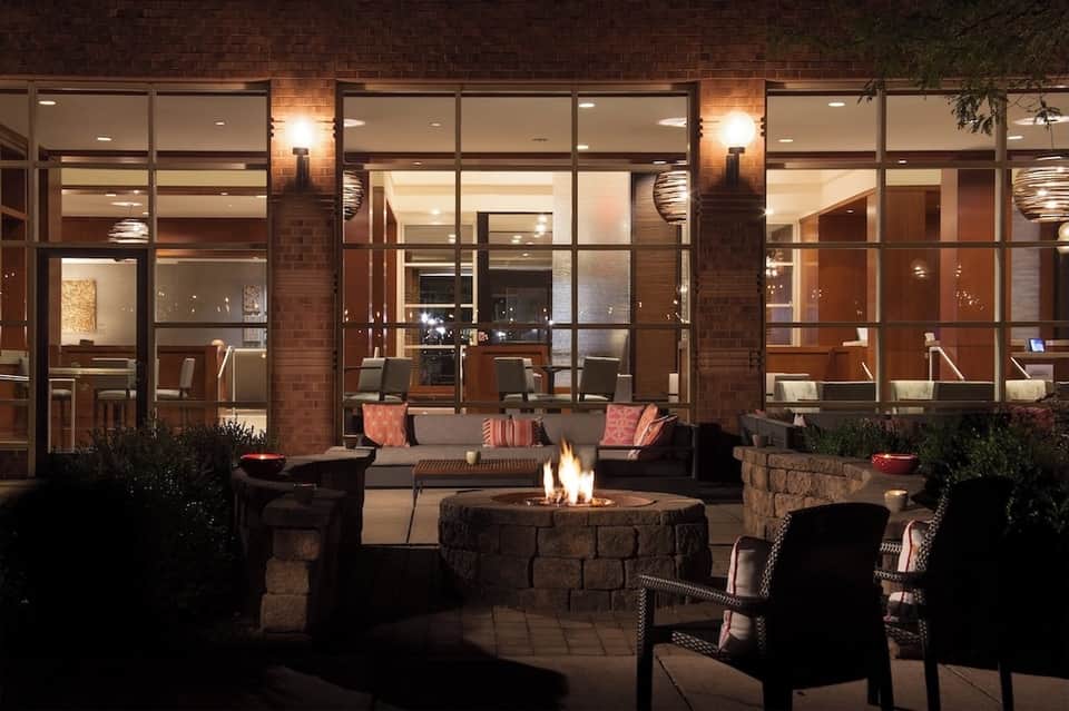 Evening courtyard with firepit seating, modern building facade with lit windows