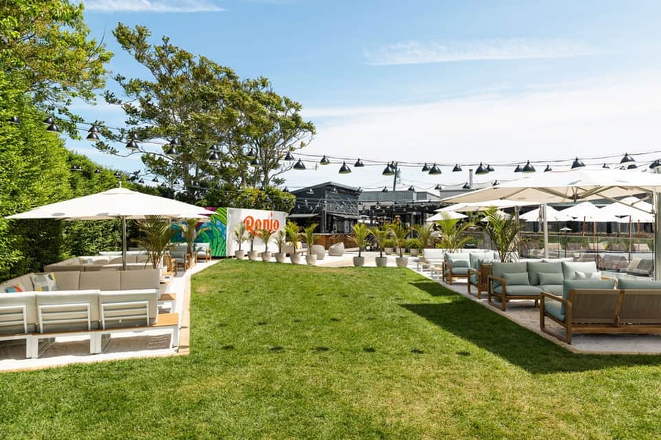 Expansive resort lawn with lounge chairs, umbrellas, and dining pavilion with hanging lights