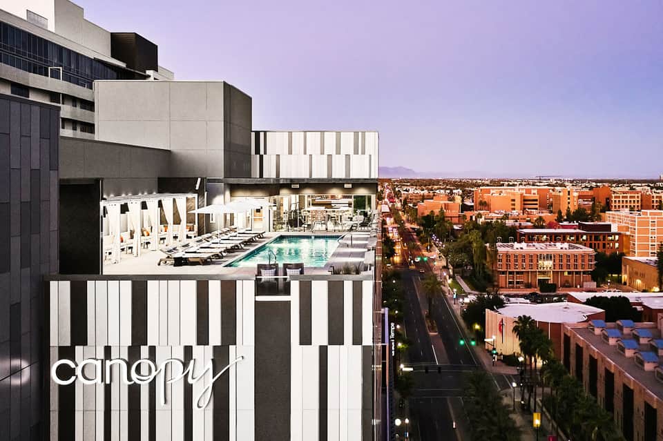 Modern hotel rooftop pool with city skyline views and desert landscape in background