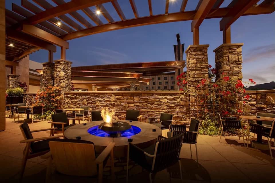Upscale outdoor patio with firepit, stone columns, and evening ambient lighting