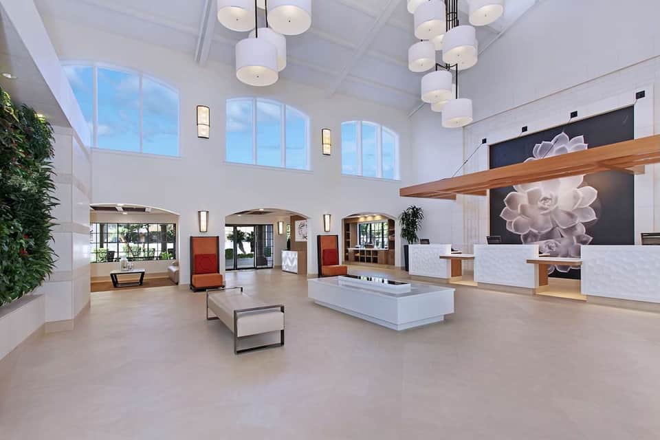 Bright modern hotel lobby with high ceilings, skylights, pendant lights, and reception desk
