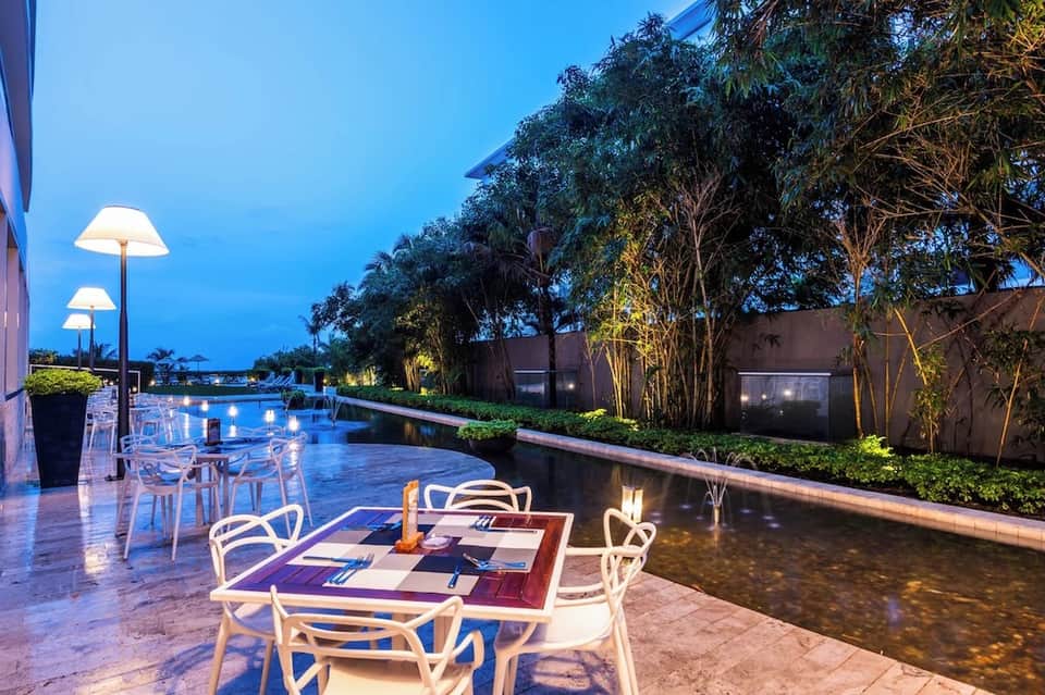 Elegant outdoor dining terrace at dusk by canal with lighting and bamboo trees
