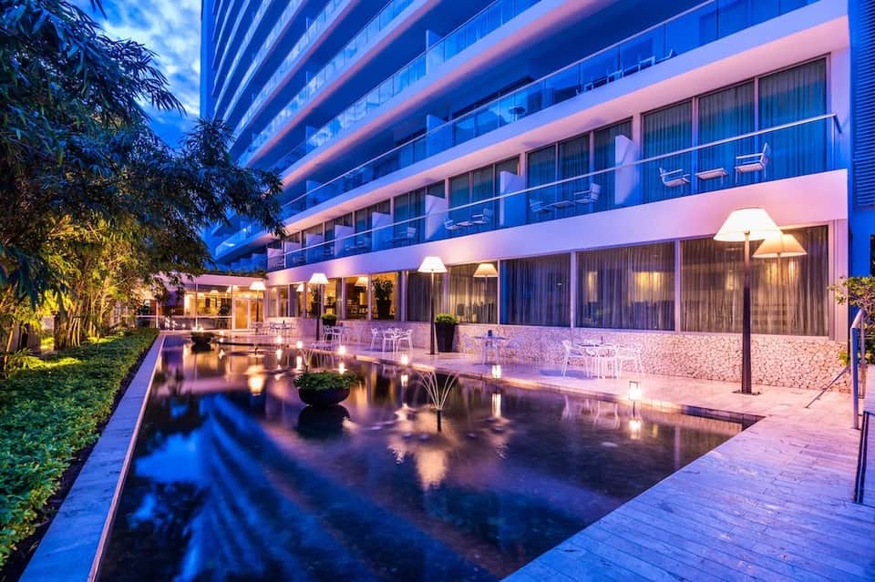 Modern resort building at dusk with pink and blue lighting and water features