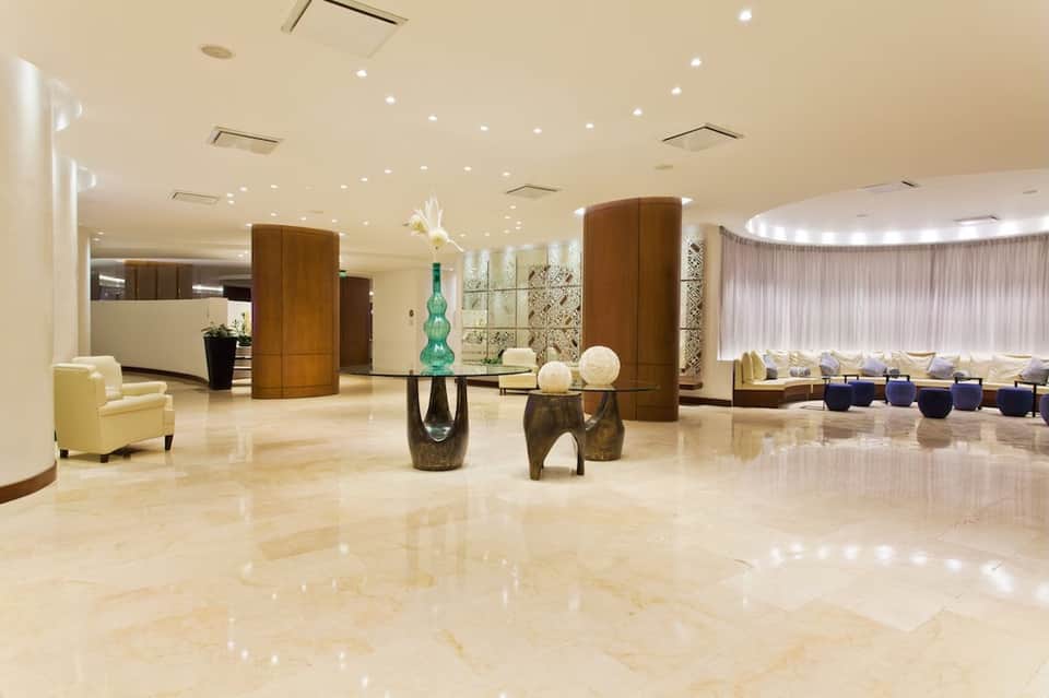 Elegant hotel lobby with polished marble floors, wooden columns, and contemporary furnishings