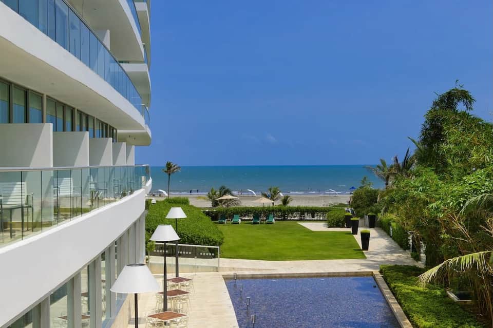 Beachfront modern building with grass lawn, pool, and ocean views