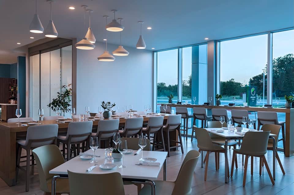 Modern waterfront restaurant with floor-to-ceiling windows and pendant lighting