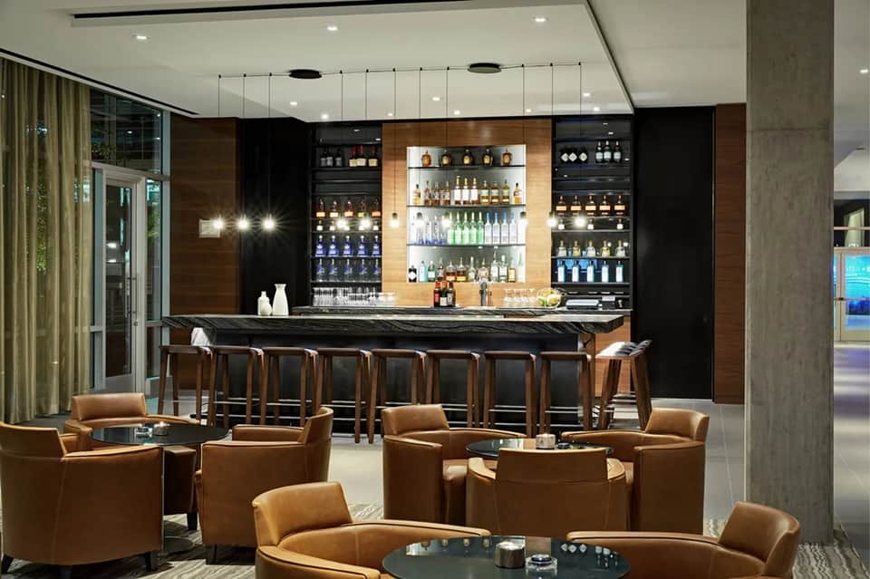 Contemporary bar lounge with backlit shelving displaying spirits, leather seating, and modern design