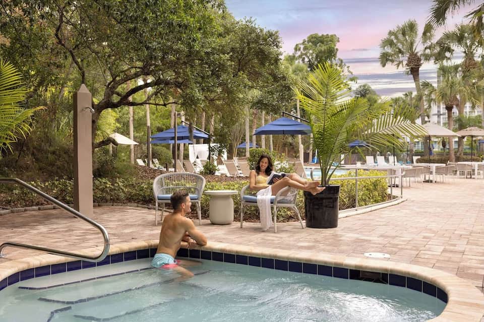 Beachfront lounge area with spa pool, palm trees, and ocean views at dusk