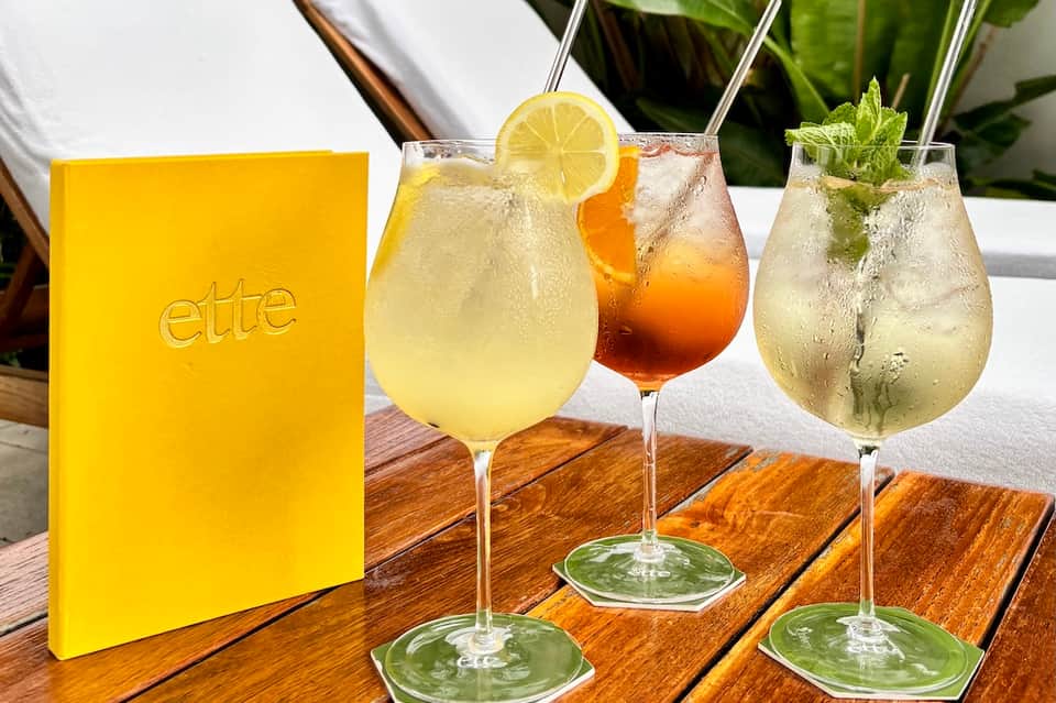 Three craft cocktails displayed with yellow menu on wooden table