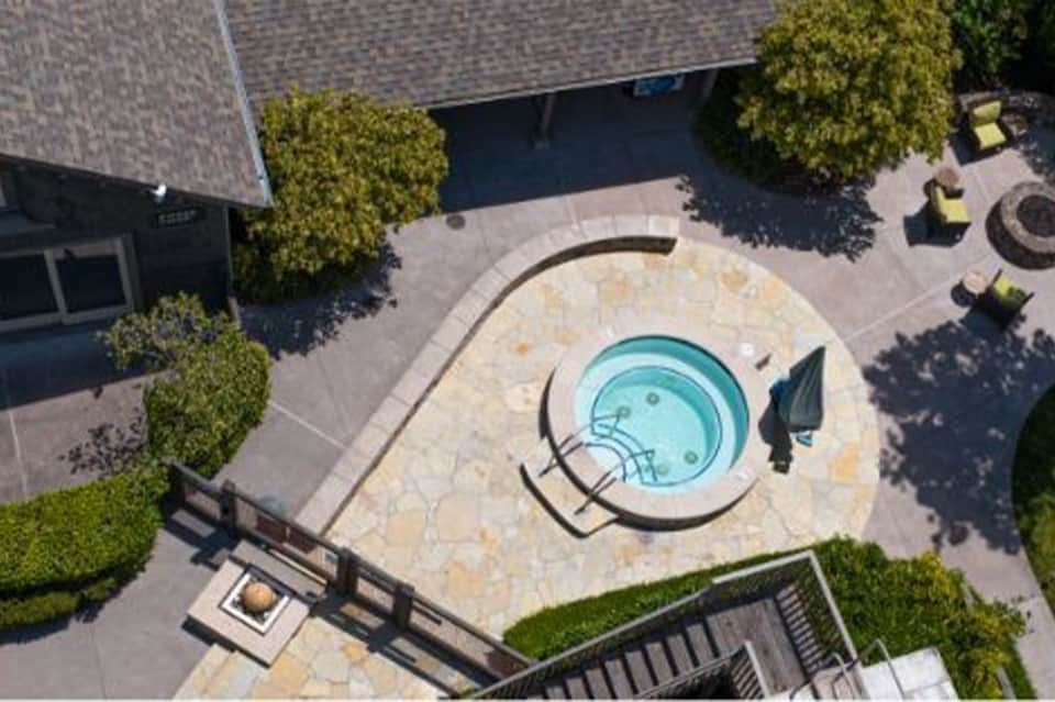 Aerial view of circular hot tub on stone patio surrounded by landscaping and building