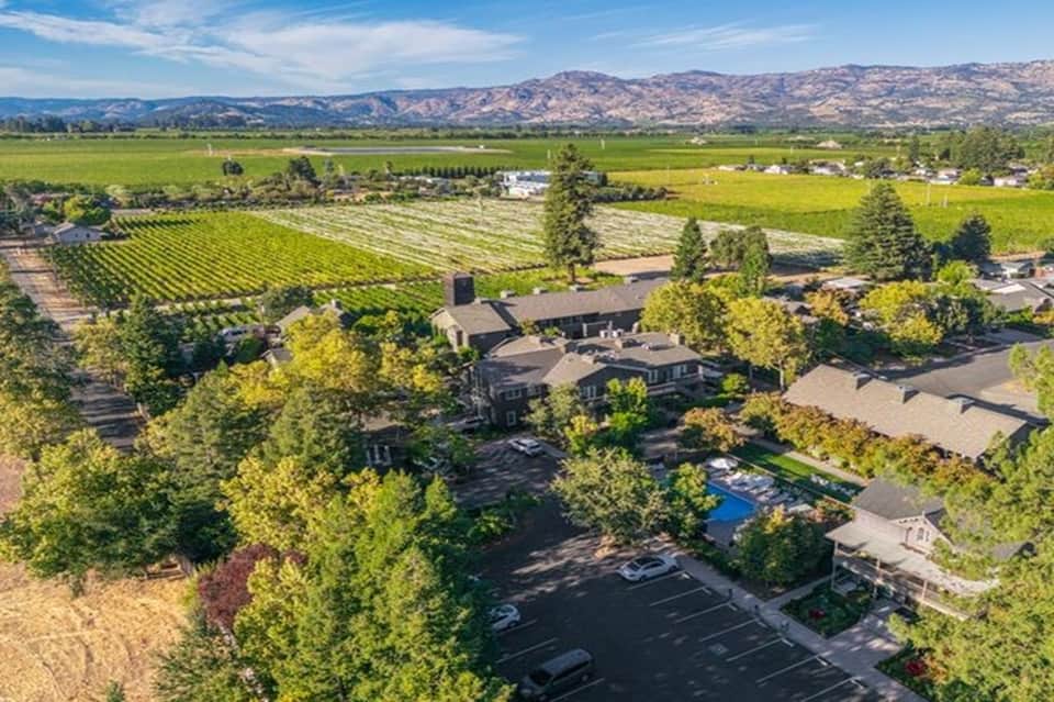 Aerial view of winery resort nestled in vineyard valley with mountains and green fields