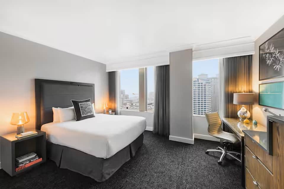 Upscale hotel room with city view, modern furnishings, and work desk