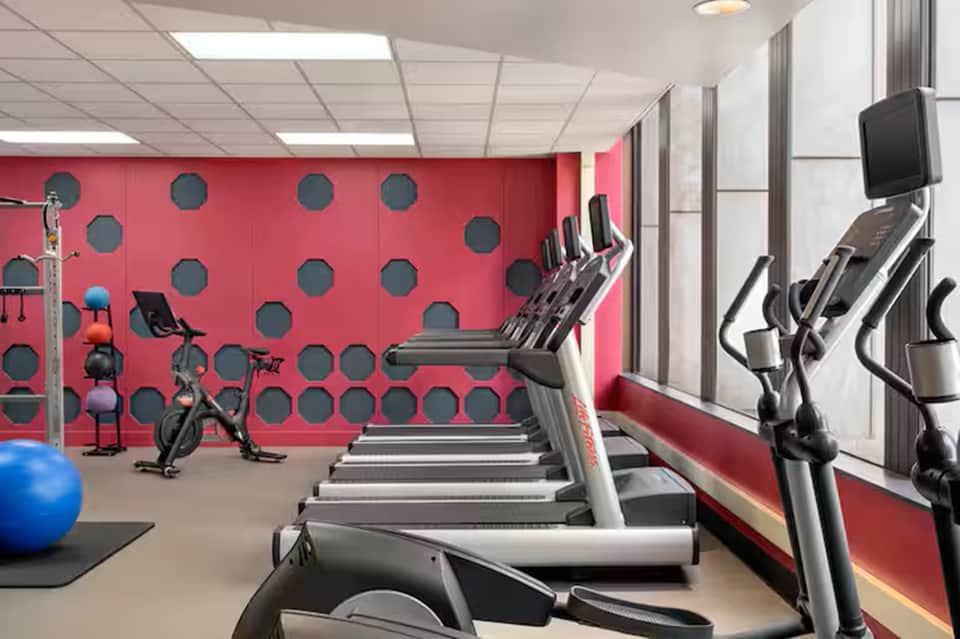 Colorful fitness center with pink walls, treadmills, exercise bikes, and gym equipment