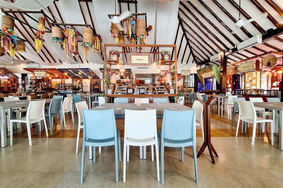 Spacious restaurant interior with high ceiling, exposed beams, and colorful hanging decorations