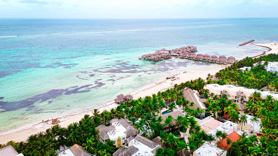 Aerial view of tropical overwater bungalows and beach resort with crystal-clear turquoise water