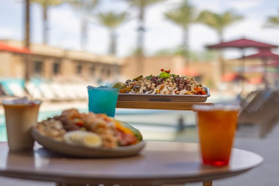 Beachside dining table with colorful salads, drinks, and ocean view in background