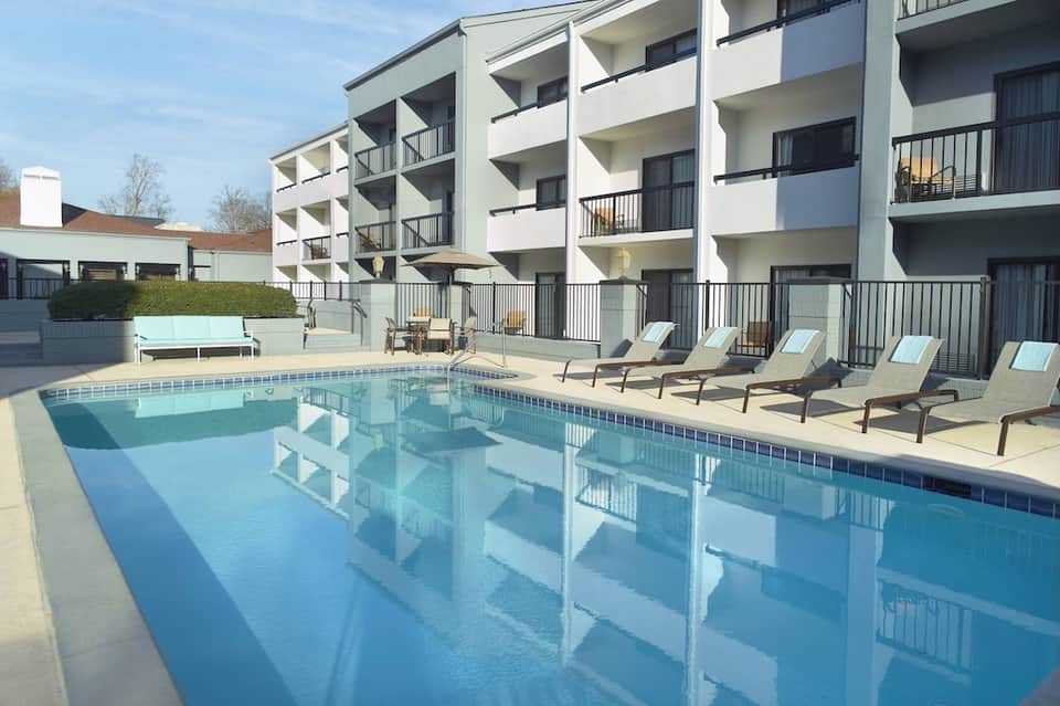 Contemporary resort pool with clear water, lounge chairs, and white residential building backdrop
