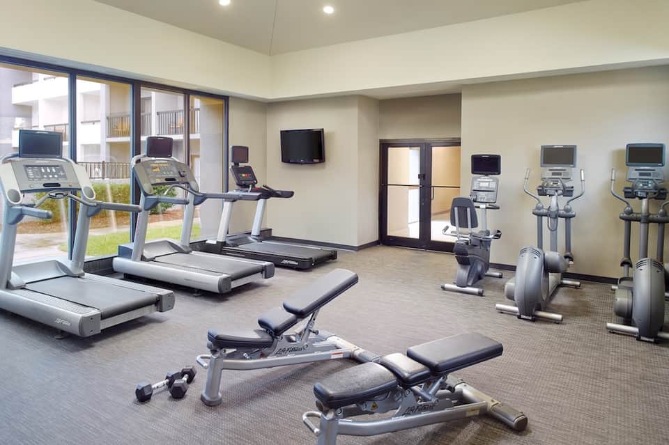 Fitness center with treadmills, stationary bikes, free weights, and glass doors to outdoor area
