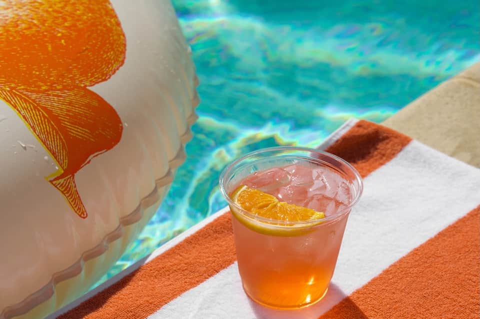 Colorful tropical drink with lemon slice by resort pool overlooking turquoise water