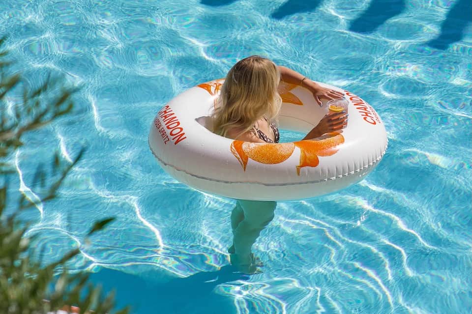 Young child floating in bright blue pool water on inflatable donut ring