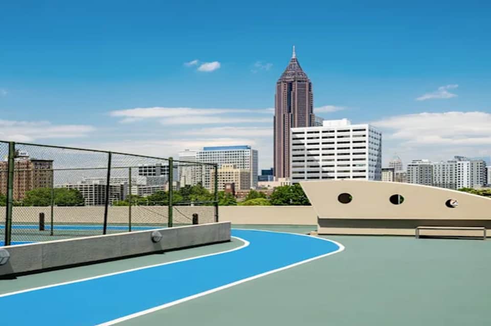 Rooftop basketball court with city skyline and tall building in background