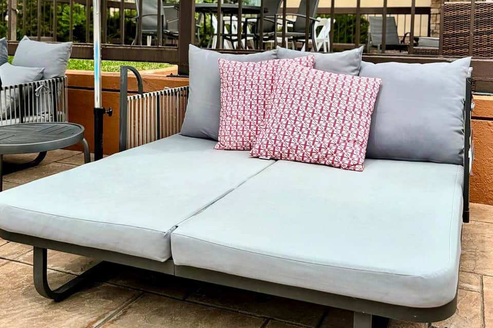 Outdoor daybed with white mattress and pink patterned cushions on patio
